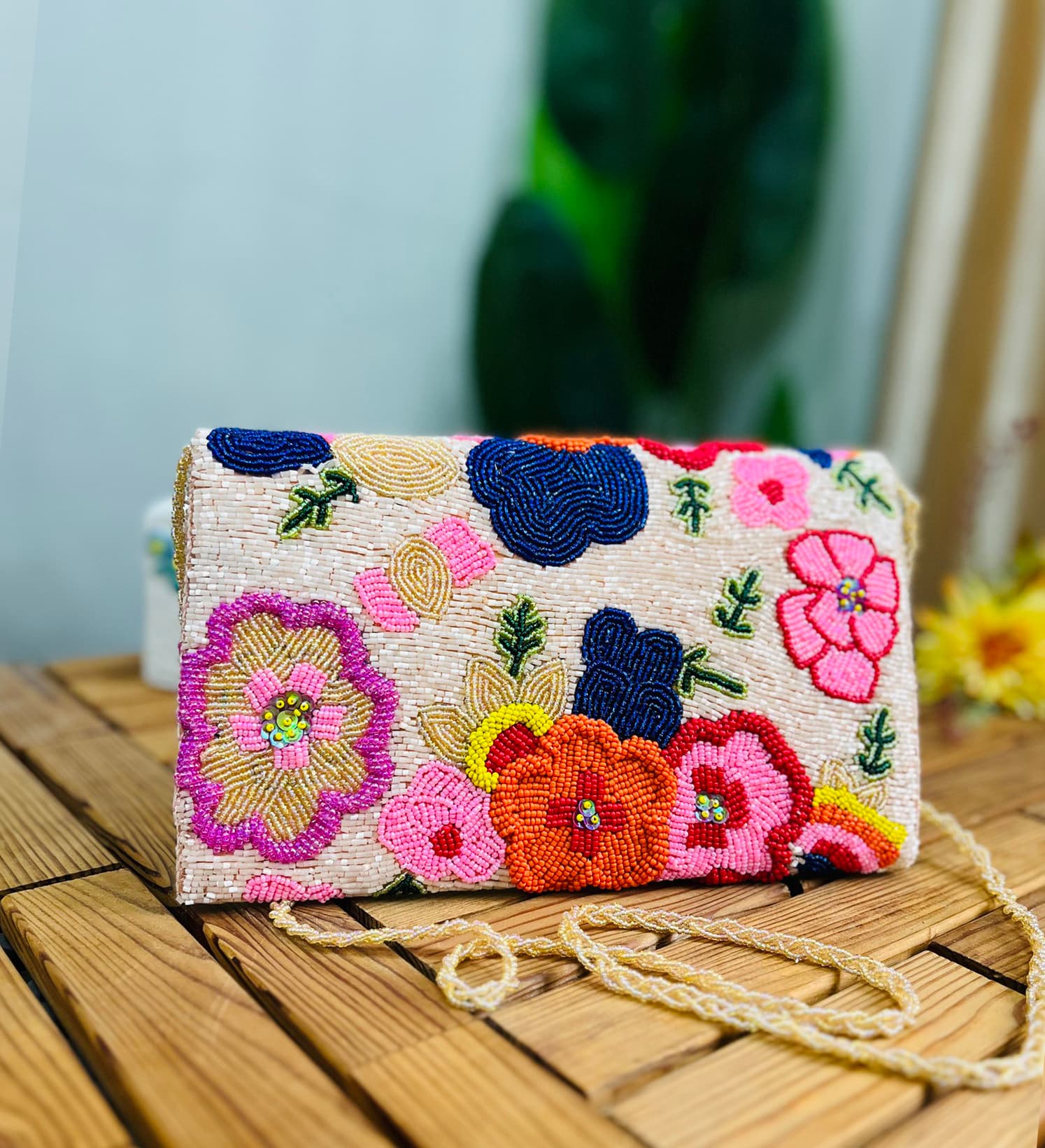 Hand-beaded envelope clutch with floral blossom design, vibrant beads, intricate patterns, tan background from Zara Label.