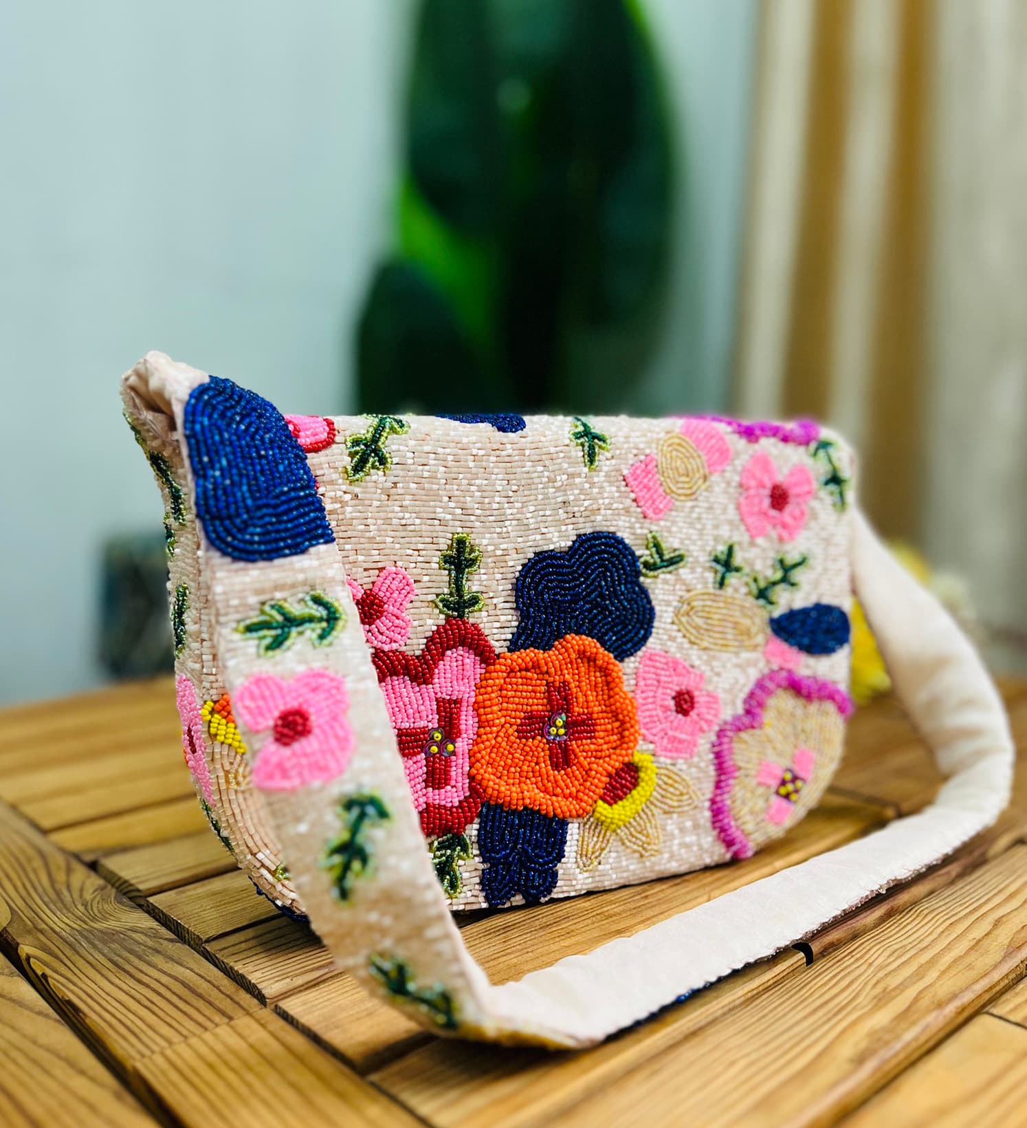 A colorful, hand-beaded shoulder bag featuring intricate floral designs, shown against a plain background, highlighting the