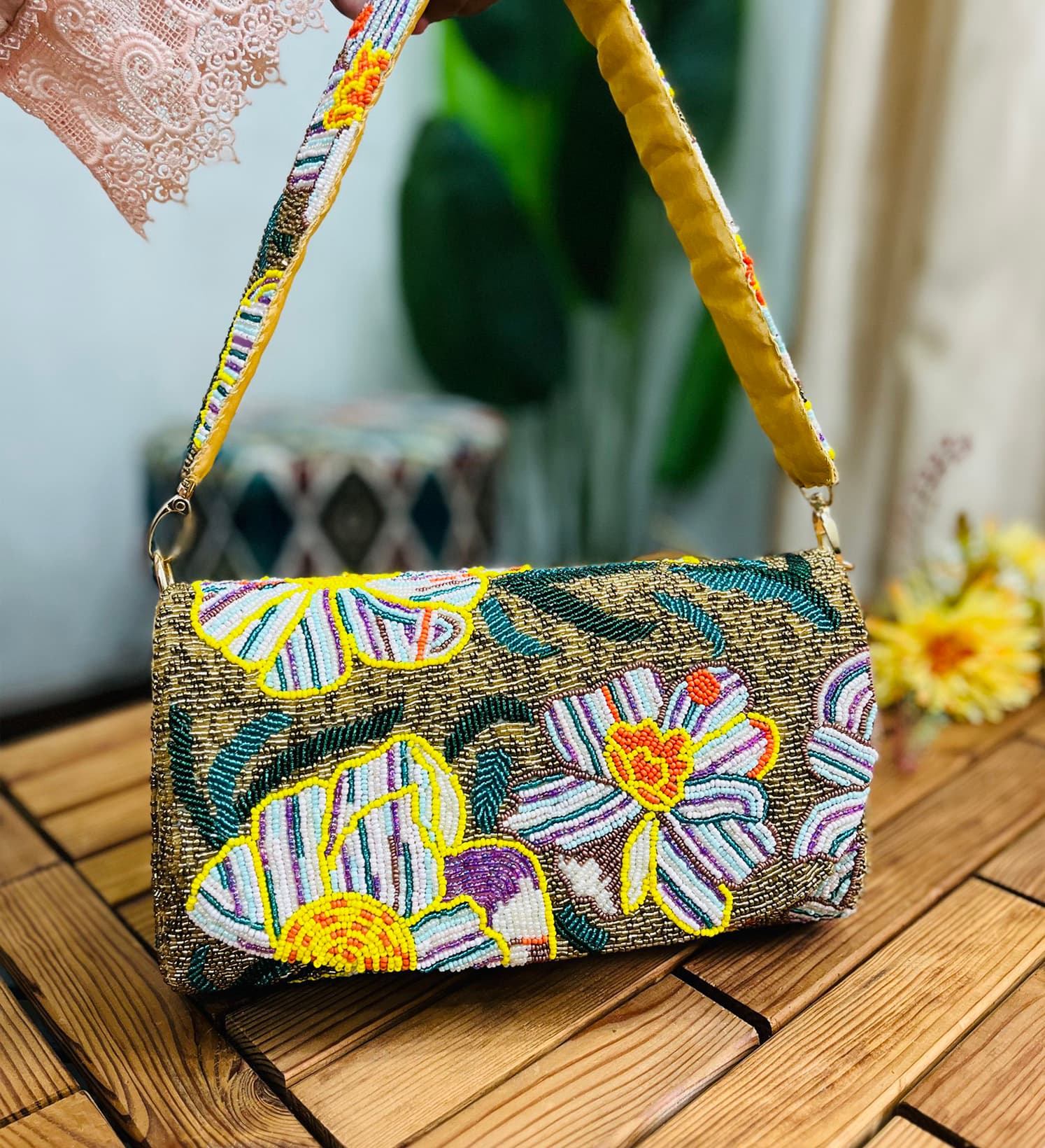 Gold shoulder bag with intricate floral beadwork, featuring a statement design, against a plain background.