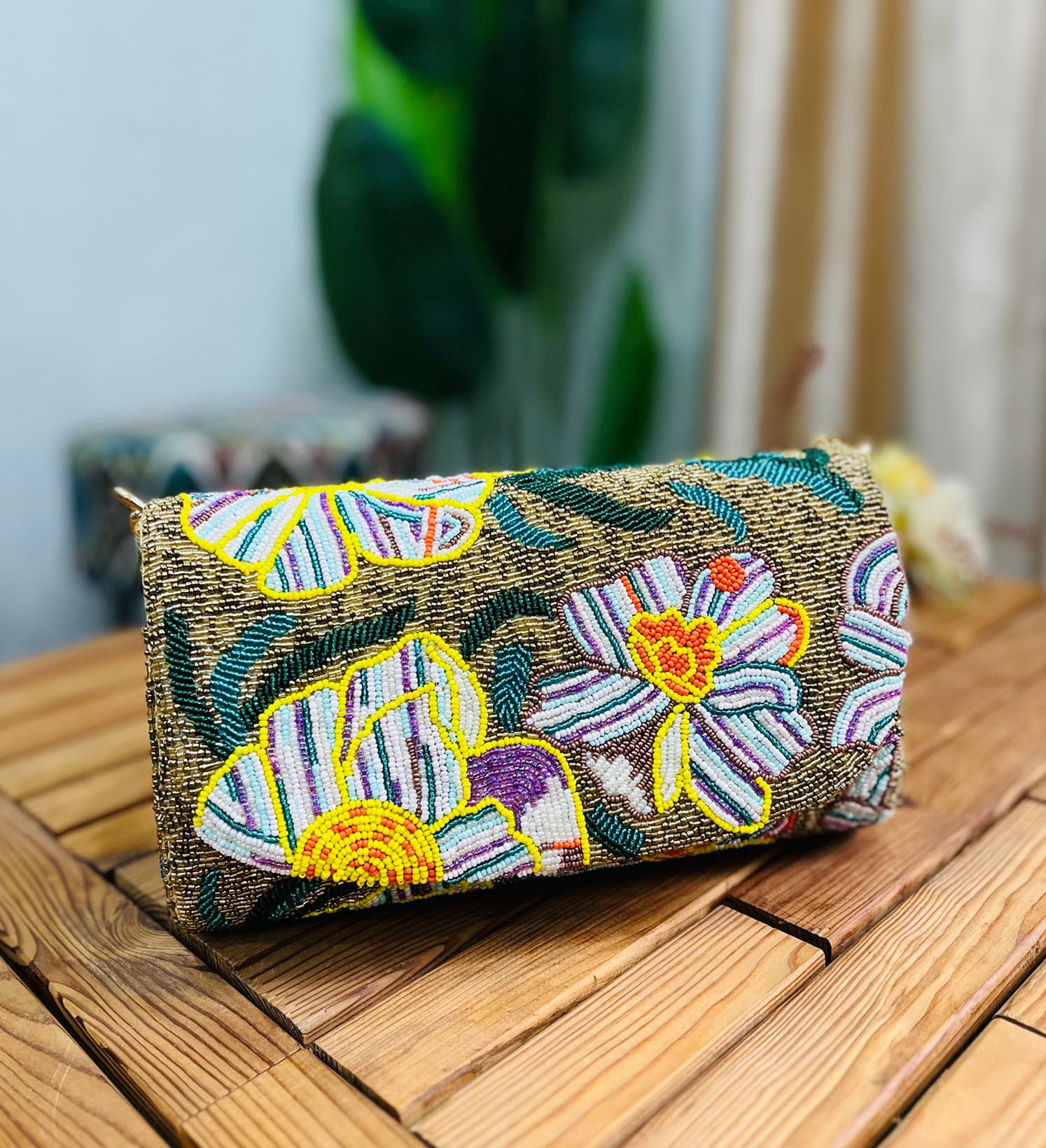 Gold shoulder bag adorned with intricate floral beadwork, featuring a statement design by Zara, displayed against a plain