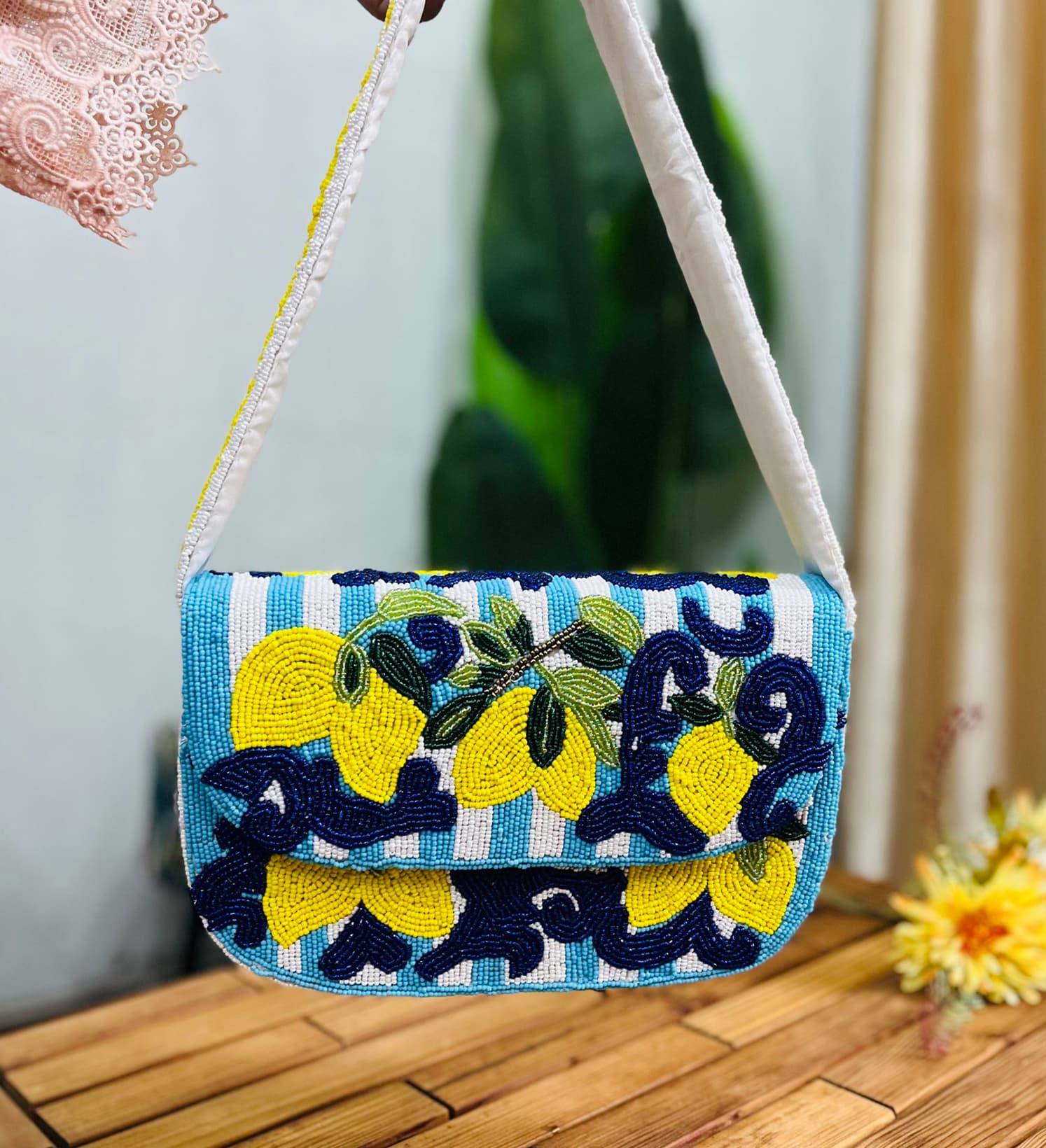 A rectangular shoulder bag beaded with lemon motifs on a white background, featuring a chain strap and a zip closure.